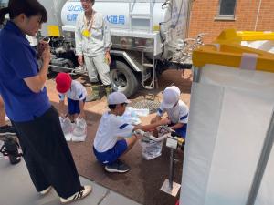児童がタンクから給水バックに補水する